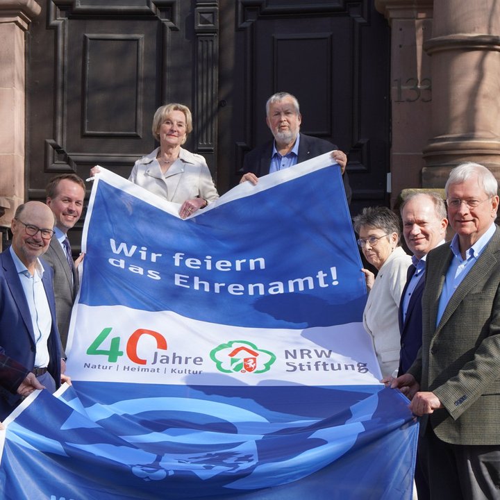 Vorstand der NRW-Stiftung und Vorsitzender des Fördervereins präsentierren Fahne 40 Jahre NRW-Stiftung