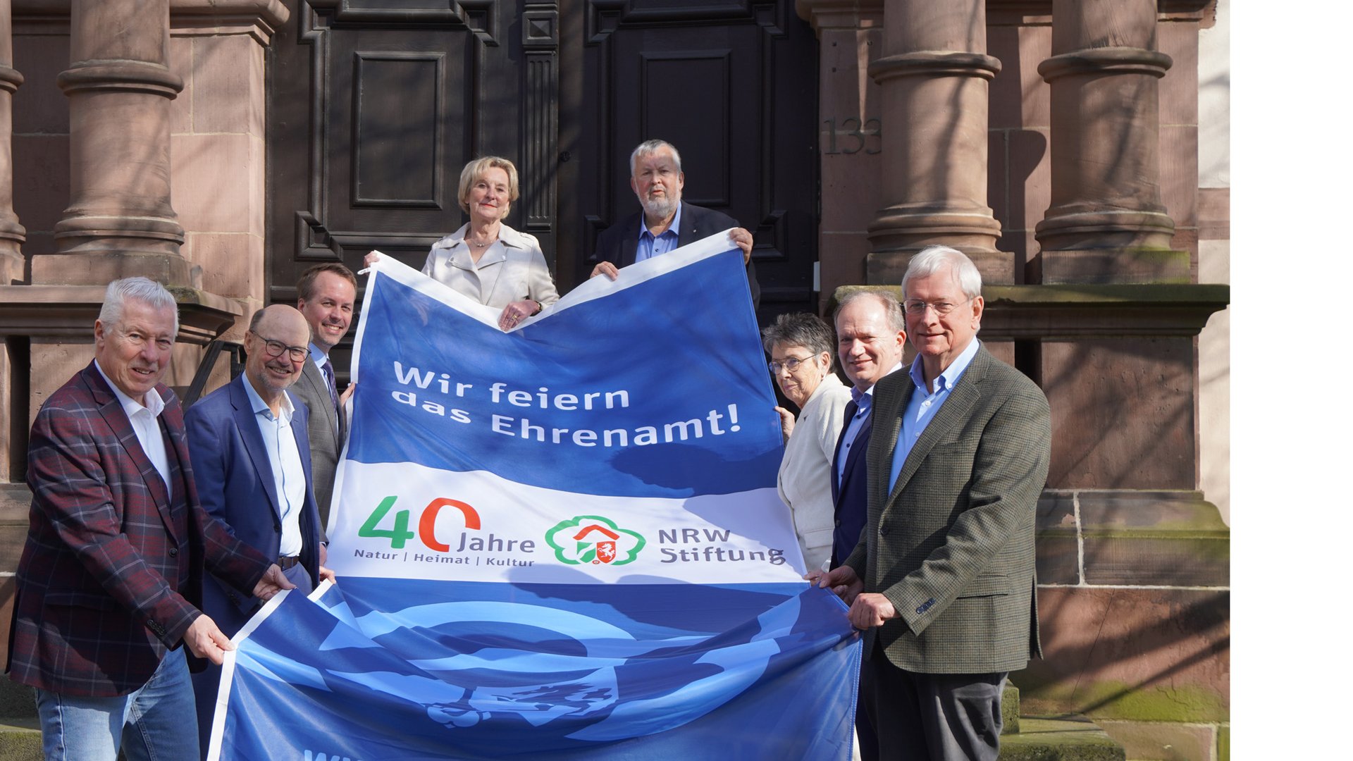 Vorstand der NRW-Stiftung und Vorsitzender des Fördervereins präsentierren Fahne 40 Jahre NRW-Stiftung